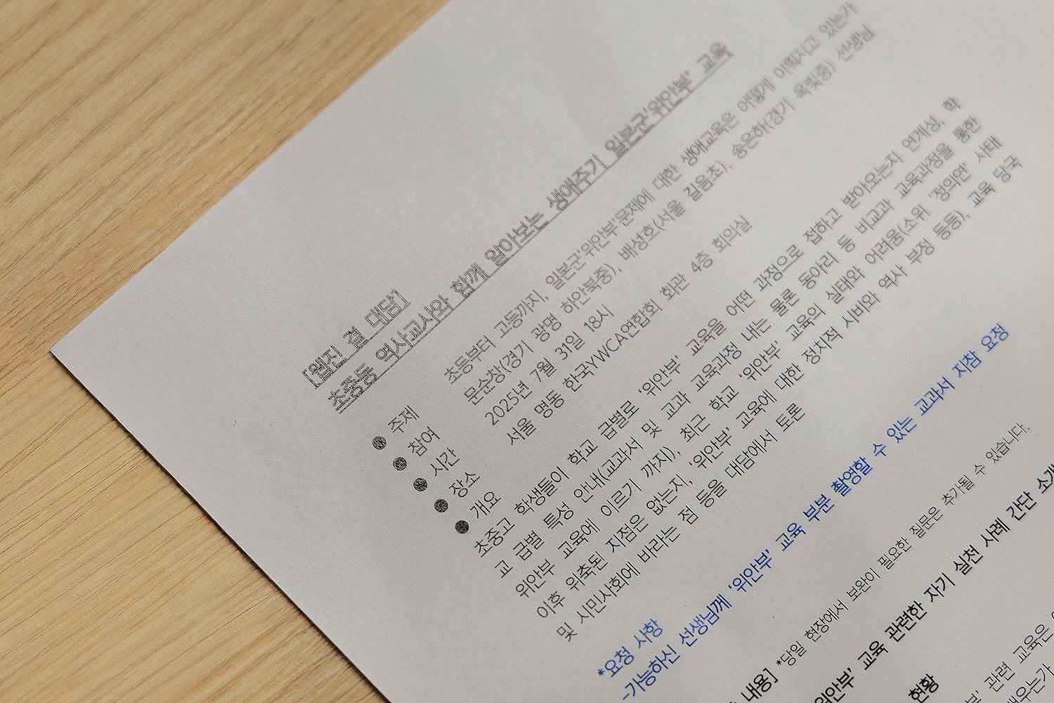 나무 책상 위에 놓인 「[웹진 결 대담] 초중등 역사교사와 함께 알아보는 생애주기 일본군&lsquo;위안부&rsquo; 교육」 대담 안내 문서. 주제, 참여자, 시간, 장소, 개요가 적혀 있음.